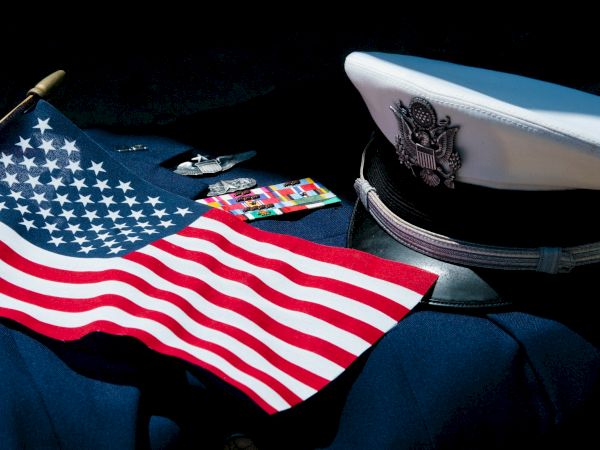 American flag on a dark surface with a navy cap and some badges, small cards; patriotic display style.